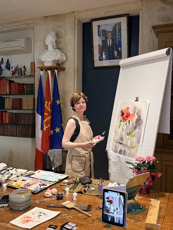 Tatsiana Harbacheuskaya giving a live watercolor demonstration, painting a floral still life at the Rencontres Lun'Aquarelle exhibition in France.